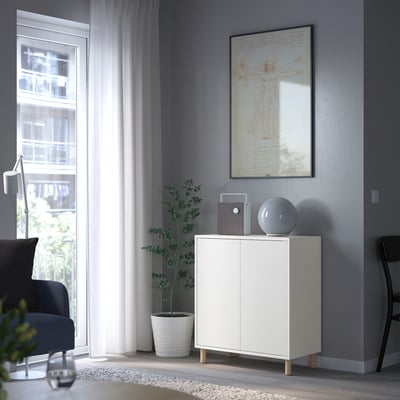 Sala d'estar moderna amb armari EKET, altaveu, llum, estampat da vinci, cadira blava, planta, finestra de cortina transparent.