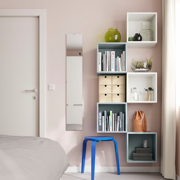 Dormitori modern amb parets roses, emmagatzematge EKET, llibres, gerros, maquillatge, tamboret blau.