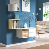 Paret blava moderna amb mobles d'emmagatzematge EKETt blancs. Obriu prestatges i calaixos, que contenen llibres i gerros, que es combinen perfectament amb l'elegant decoració de la sala d'estar.