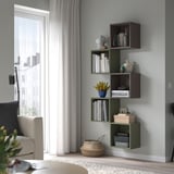 Prestatges EKET de paret en verd i marró, amb llibres, plantes i decoració. Al costat d'una gran finestra amb cortines blanques, afegeix emmagatzematge i estil moderns.