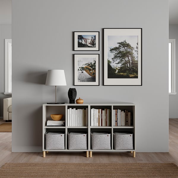 Saló minimalista amb decoració grisa, llum blanca, prestatgeria, fotos i articles de decoració.