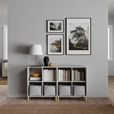 Saló minimalista amb decoració grisa, llum blanca, prestatgeria, fotos i articles de decoració.