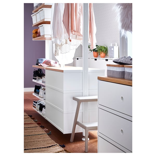 Dormitori modern amb emmagatzematge blanc, prestatgeries, calaixos, barana penjant, parets morades, catifa.