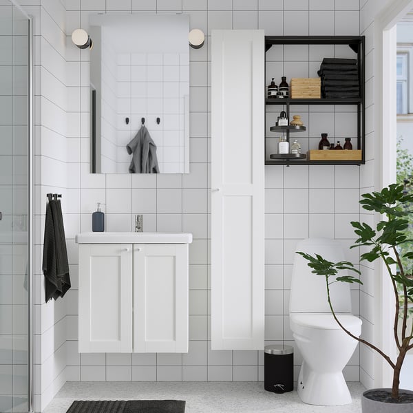 Bany minimalista amb emmagatzematge ENHET, mirall, lavabo, vàter, planta i tovallola negra.
