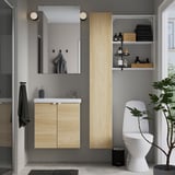 Bany minimalista amb emmagatzematge ENHET de roure clar, mirall i lavabo.