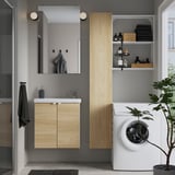Bany modern amb armari de fusta clara, rentadora blanca, accents negres i mirall.