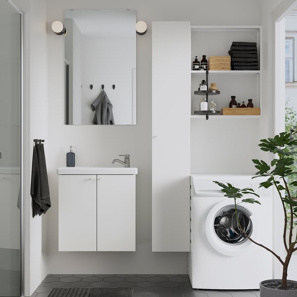 Bany modern amb armari ENHET blanc, mirall, lavabo i rentadora. Els prestatges contenen tovalloles i articles de tocador.