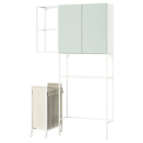 Un magatzem de bugaderia ENHET blanc amb portes verdes, amb prestatges oberts i una bossa de roba penjant.