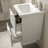 Moble de bany modern obert, mostrant calaixos organitzats: un amb maquillatge, l'altre amb tovalloles. Taulell i lavabo minimalistes.