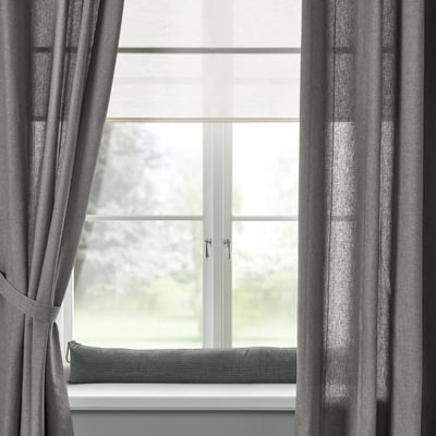 Finestra moderna amb cortines i coixí grisos; disseny minimalista.