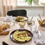 Taula amb plats, coberts i gots FÄRGKLAR, coberts amb truites i pa gourmet.