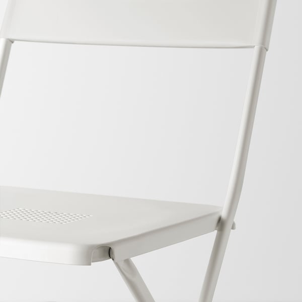 Cadira plegable blanca moderna i minimalista, feta d'acer i plàstic recobert de pols durador, que es mostra en primer pla.