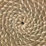 Cistella de posidònia teixida a mà, que mostra un disseny i una artesania complexos.