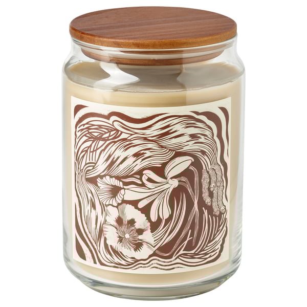Una espelma perfumada GLANSLIND en un pot de vidre transparent amb tapa de fusta. L'etiqueta té un disseny floral marró i beix. El color de les espelmes és beix.