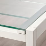 Primer pla de la taula de vidre moderna amb un marc metàl·lic resistent; disseny elegant i minimalista.