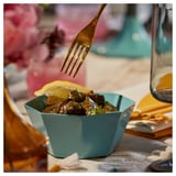 Forquilla d'aixecament d'aliments del bol blau GOKVÄLLÅ sobre taula amb tovalló.