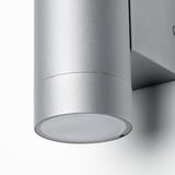Làmpada de paret cilíndrica moderna, amb un elegant acabat d'acer inoxidable, dissenyada per a ús exterior.