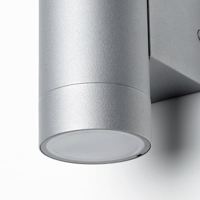 Aplic d'exterior platejat i modern, de forma cilíndrica de dues parts.