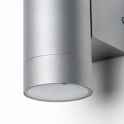 Un aplic d'exterior platejat, GRÖNSPRÖT, amb una forma cilíndrica elegant i resistent a la humitat.