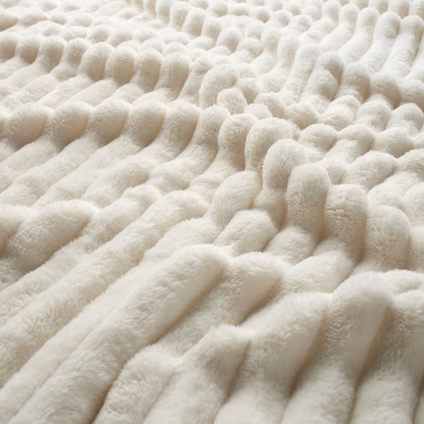 Primer pla d'una manta blanca suau i texturitzada, destacant la seva textura acollidora i acollidora.