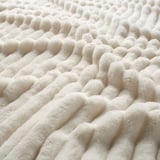 Primer pla d'una manta blanca suau i texturitzada, destacant la seva textura acollidora i acollidora.