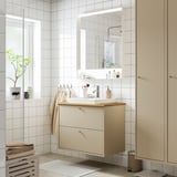 Moble de bany beix modern amb lavabo, mirall i tovalloles.