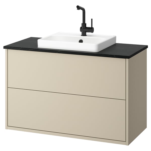 Tocador de bany beix modern amb taulell negre elegant i lavabo. Muntat a la paret amb dos calaixos per a l'emmagatzematge. Disseny elegant i funcional.