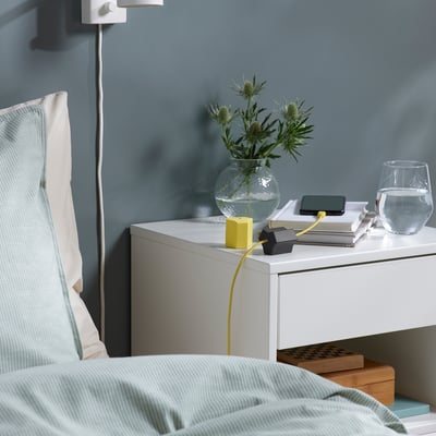 Els ancoratges USB de nit organitzen cables; El disseny groc i negre manté els cables ordenats a la tauleta de nit.