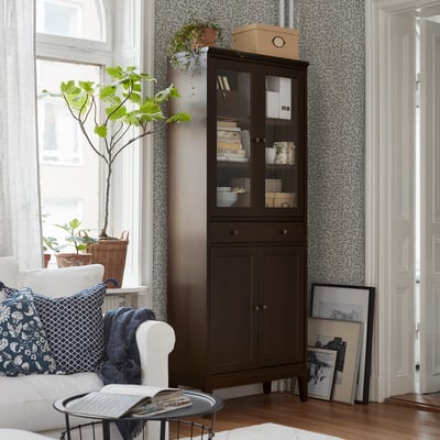 Vitrina IDANÄS gris fosc amb portes de vidre i calaixos de fusta. És un disseny elegant i modern amb una forma alta i rectangular.