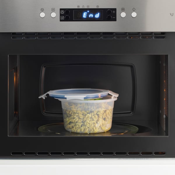 Recipient de plàstic transparent amb tapa al microones, que s'utilitza per emmagatzemar i escalfar aliments. Els clips de la tapa es tanquen per a una seguretat a prova de fuites.