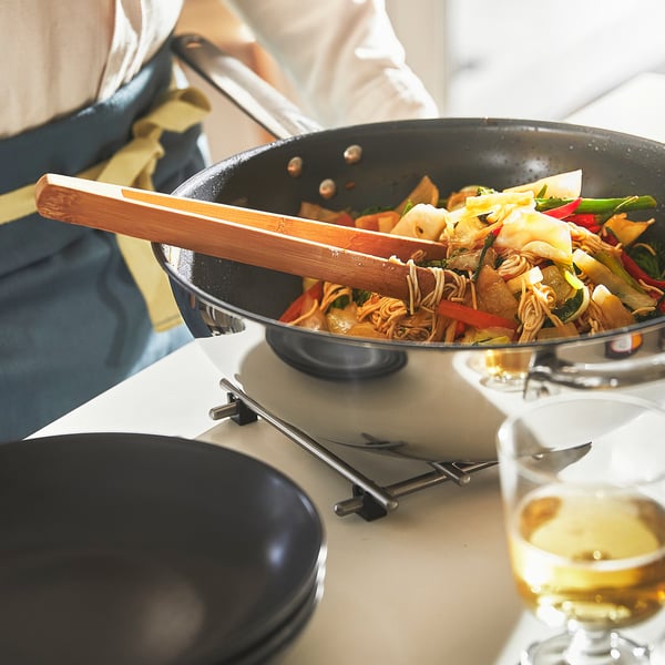Cuinar sofregit al wok amb pinces.