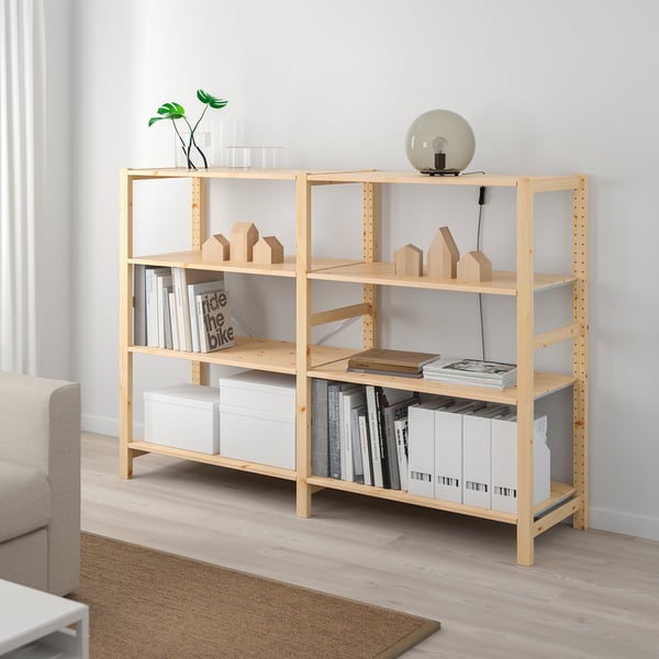 La prestatgeria de fusta clara s'adapta perfectament a l'habitació, amb llibres, caixes i decoració.