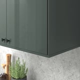 Armari brillant de color gris-verd amb nansa negra sobre el backsplash gris texturitzat, amagant cordons i il·luminació a sota.