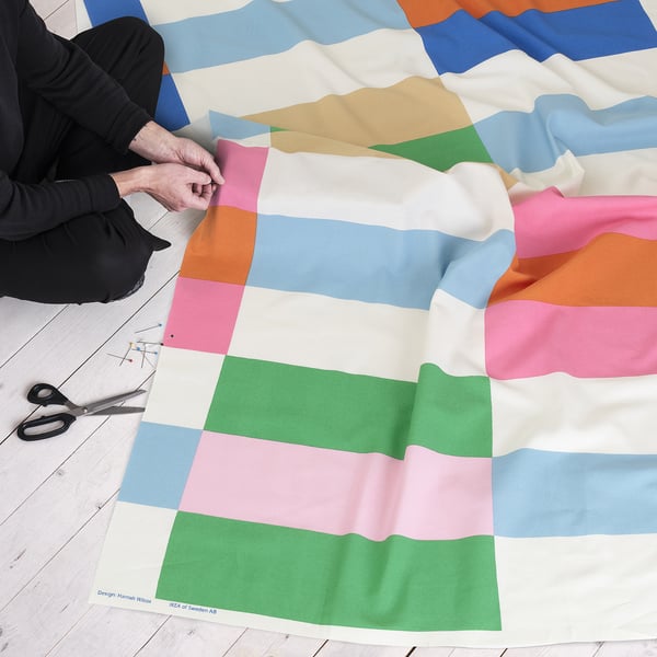 Persona que talla teixits amb estampats de quadrícules de colors per al projecte de costura.