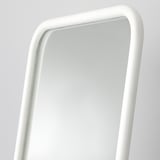 Un mirall blanc elegant i sense marc amb vores llises, que reflecteix una habitació lluminosa, garanteix una visió clara.