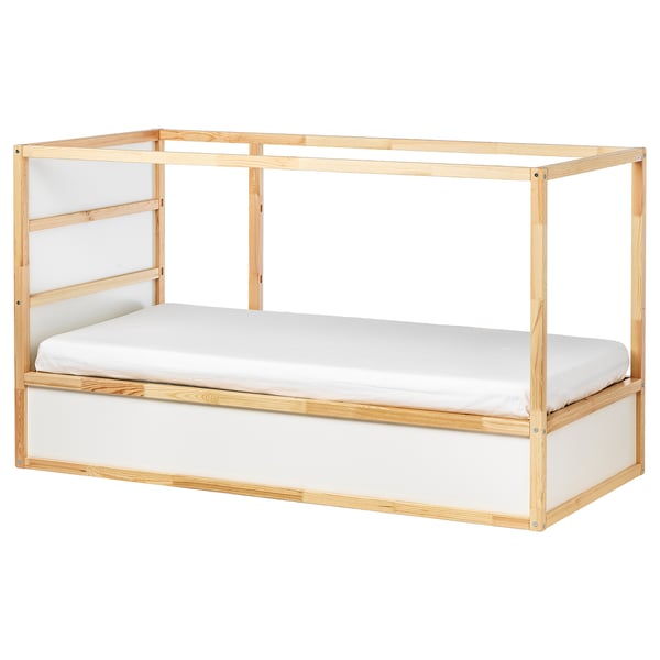 Un llit KURA de color fusta clar amb un matalàs blanc, amb un disseny minimalista i un marc resistent.