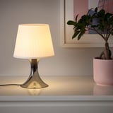 Llum petita al taulell, llum càlida, ombra blanca, base moderna, crea un ambient acollidor.