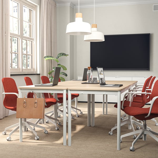 Sala de conferències moderna amb cadira d'oficina LÅNGFJÄLL taronja, ordinador portàtil, TV i planta.