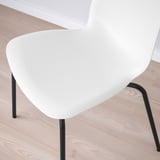 Cadira blanca moderna, disseny elegant, seient corbat, potes metàl·liques negres. Perfecte per a una decoració minimalista.