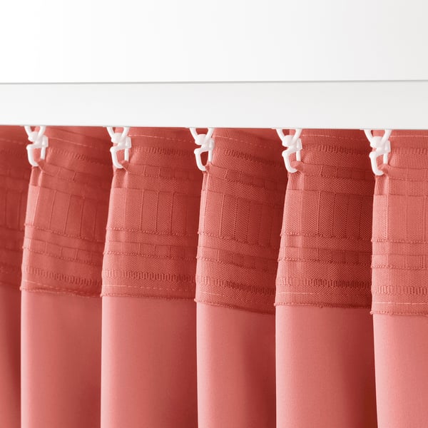 Quatre cortines roses que enfosqueixen l'habitació pengen perfectament, unides amb ganxos blancs, proporcionant privadesa i bloquejant la llum amb el seu material gruixut.