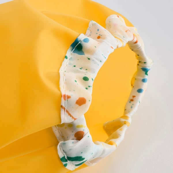 Davantal groc vibrant amb teixit impermeable i resistent i corretja ajustable al coll, dissenyat per protegir-se durant les activitats creatives.
