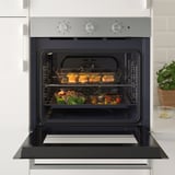 La imatge mostra un forn obert d'acer inoxidable amb funció de convecció, cuinant diversos plats en diversos prestatges.