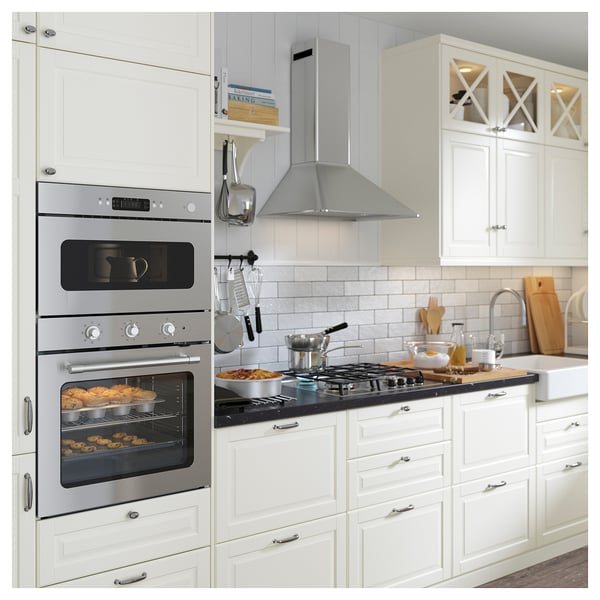 Cuina moderna amb forn doble d'acer inoxidable i fogons de gas, armaris blancs, taulell negre.