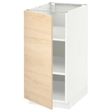 Un armari obert de color blanc amb porta de fusta clara que mostra prestatges interiors, part del sistema de cuina METOD.