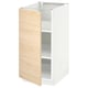 Un armari obert de color blanc amb porta de fusta clara que mostra prestatges interiors, part del sistema de cuina METOD.