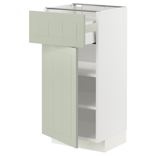 Un armari de cuina METOD blanc amb portes i prestatges verds. Té un disseny modern i minimalista amb un calaix obert i una porta batent.