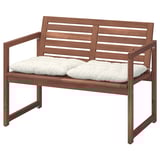 Banc exterior de fusta d'acàcia marró amb coixins blancs, respatller inclinat i reposabraços.