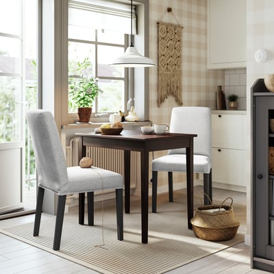 Configuració moderna del menjador amb taula fosca, cadires grises i decoració.