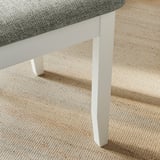 Un racó d'una cadira d'estil de pagès moderna i ben elaborada amb una pota de fusta blanca resistent i un seient encoixinat gris.