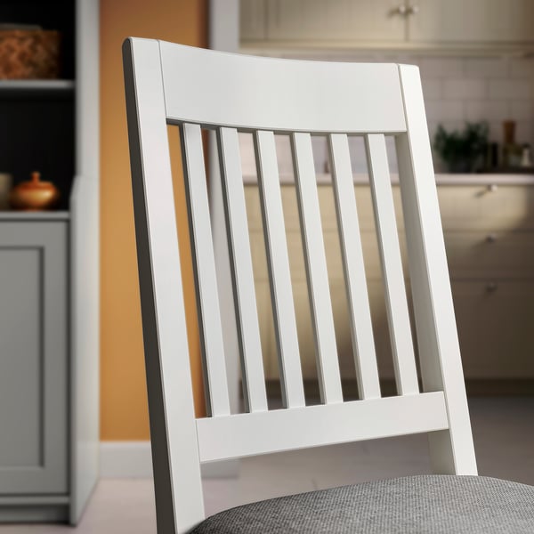 Primer pla d'una cadira de fusta blanca elegant i d'alta qualitat amb respatller vertical i seient entapissat.